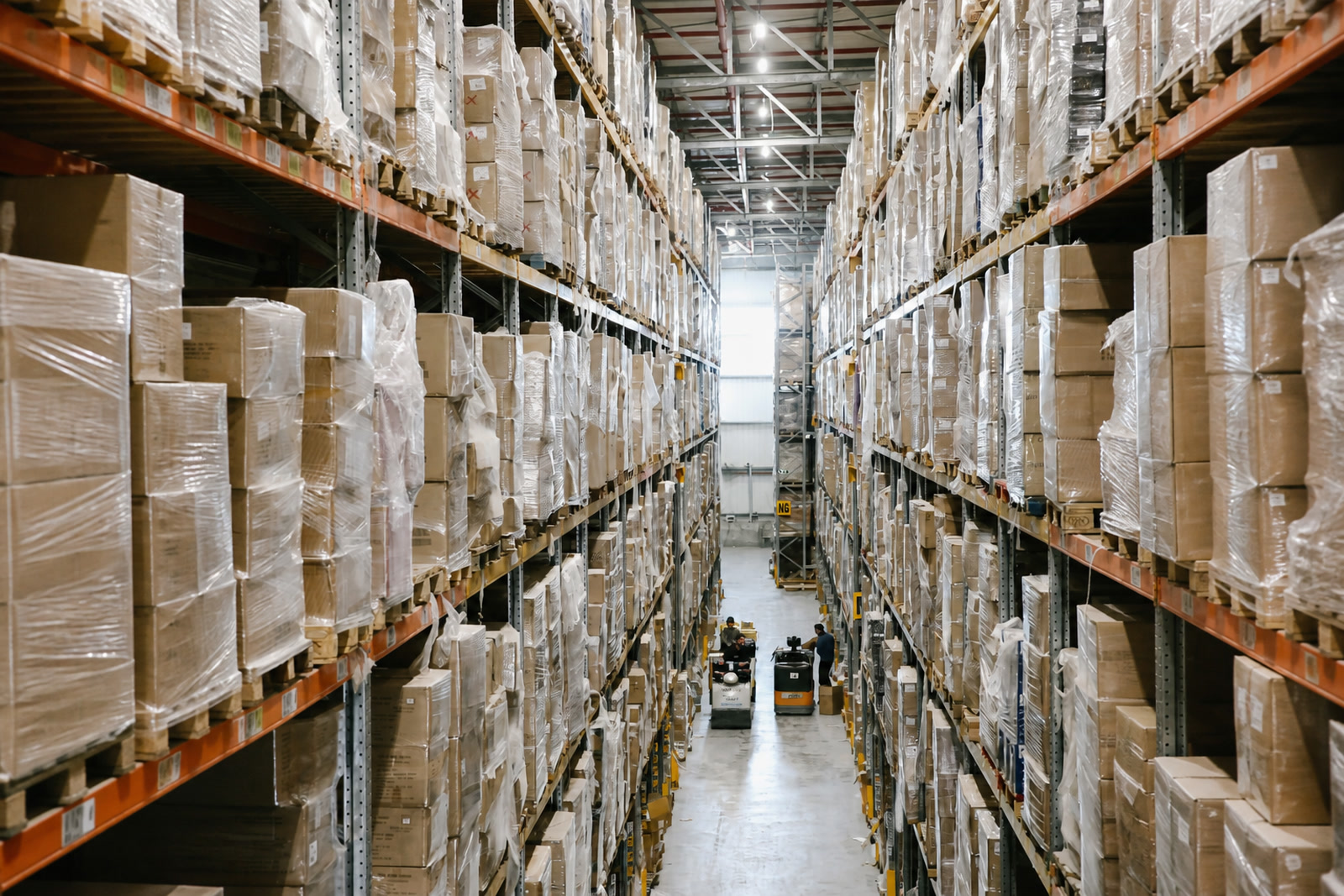Warehouse shelving filled with inventory along a deep central aisle