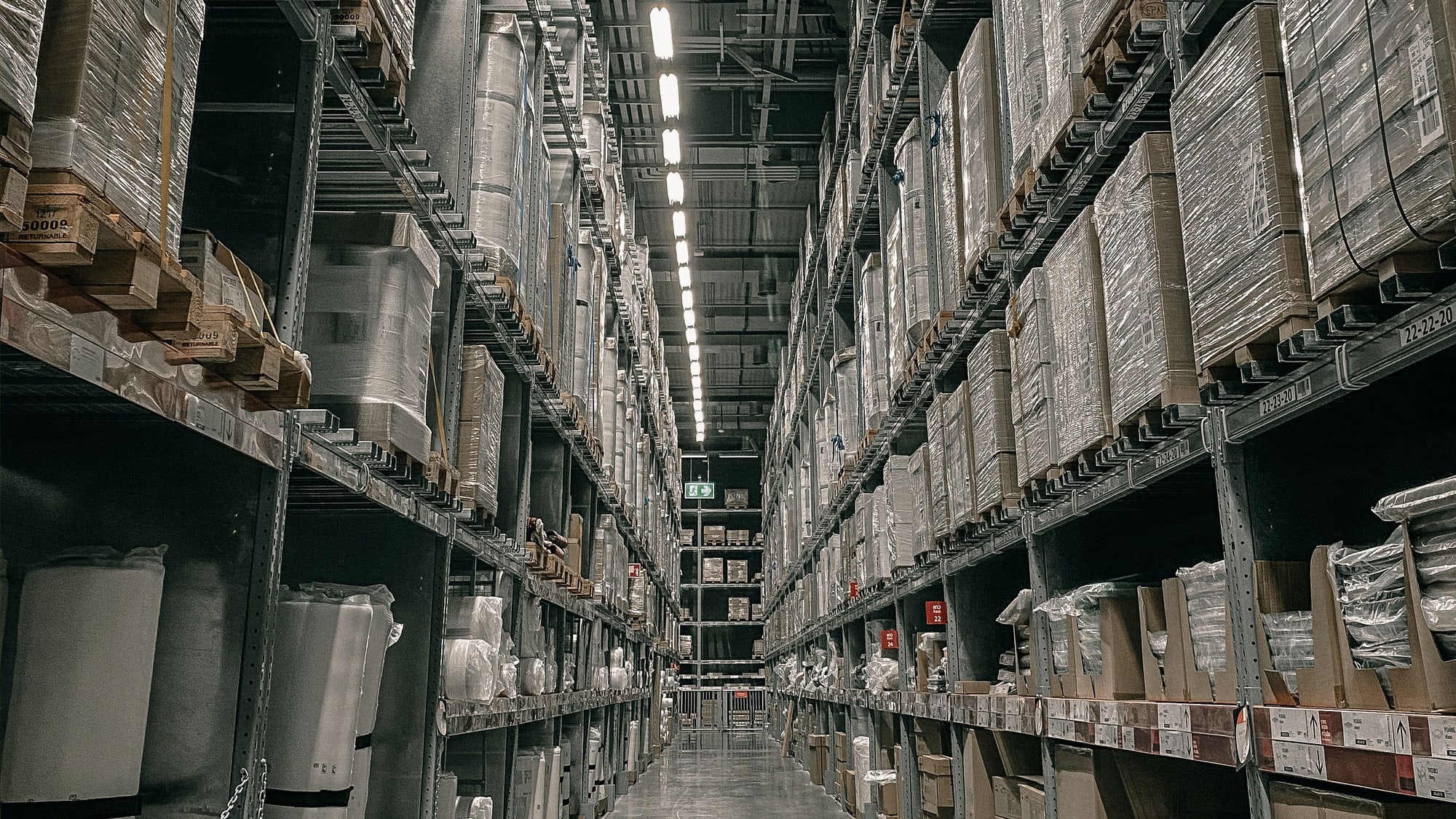Warehouse aisle with shelving, pallets and inventory stretching into the distance